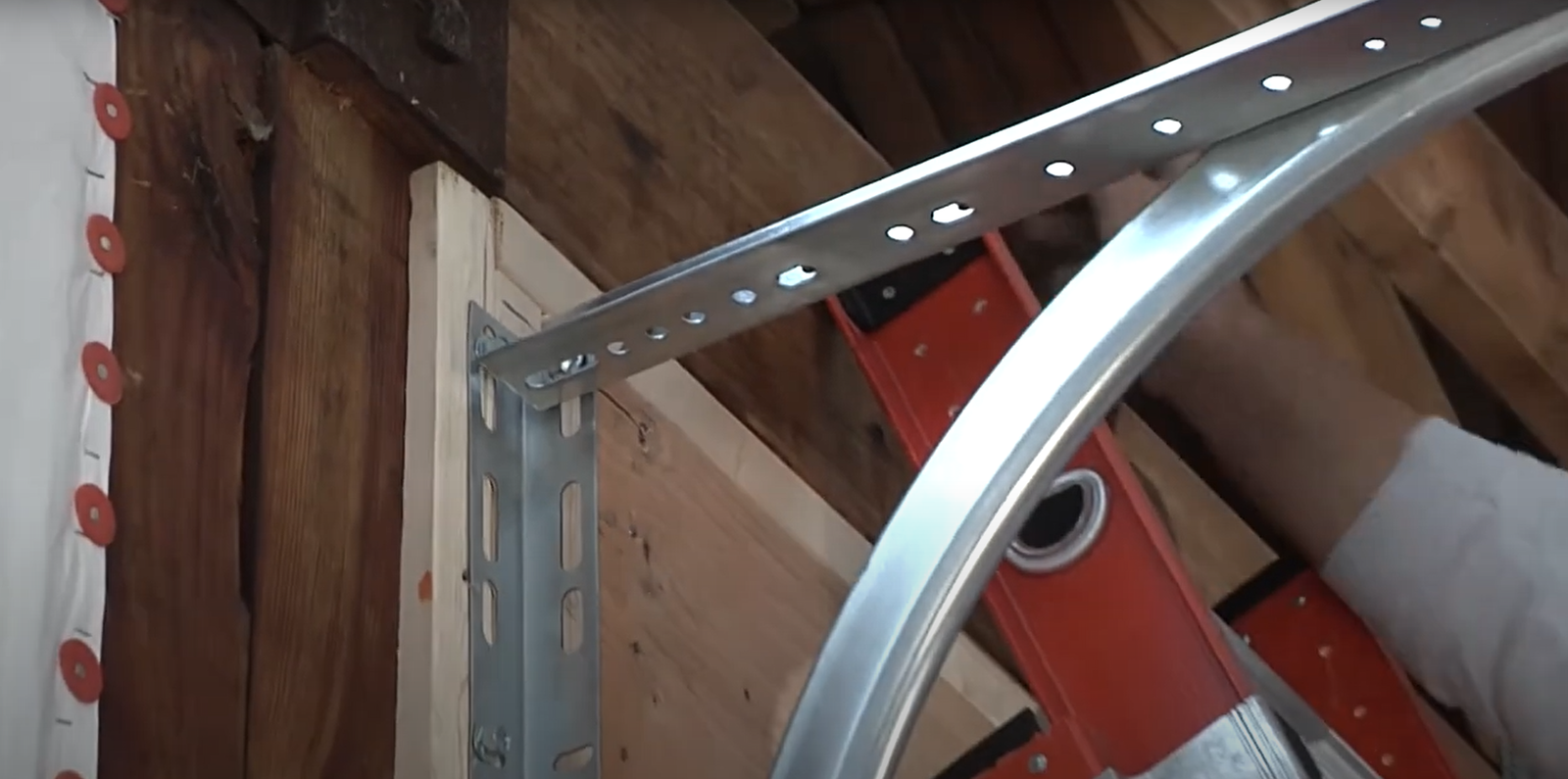 Technician repairing a garage door track with tools, showcasing precision and expertise in garage door track repair.