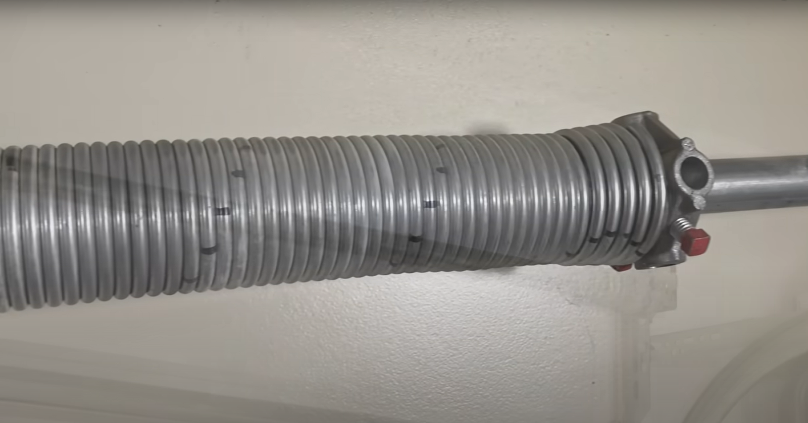 Professional technician repairing a garage door spring with specialized tools in a residential garage, showcasing expert garage door spring repair services.